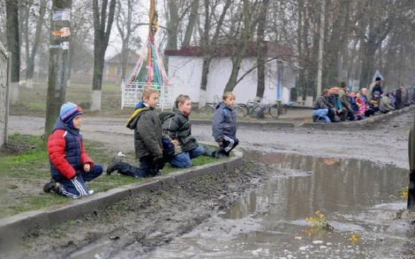 Детей поставили в грязь на колени, во время похорон укрокарателя - ФОТО